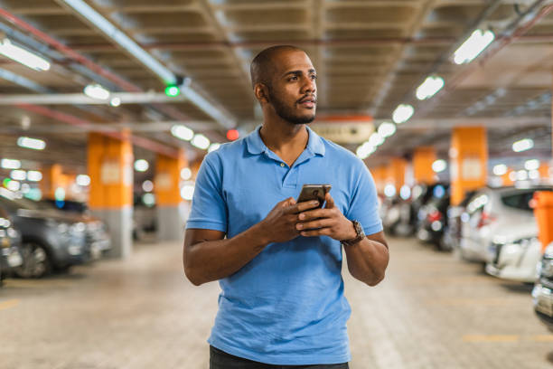 Man holding smartphone in parking lot. Man holding smartphone in parking lot.